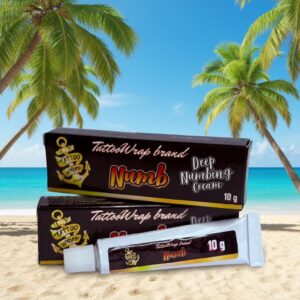 Box and tube of TattooWrap brand Numb Deep Numbing Cream on a sandy beach with palm trees; 10 g tubes visible.